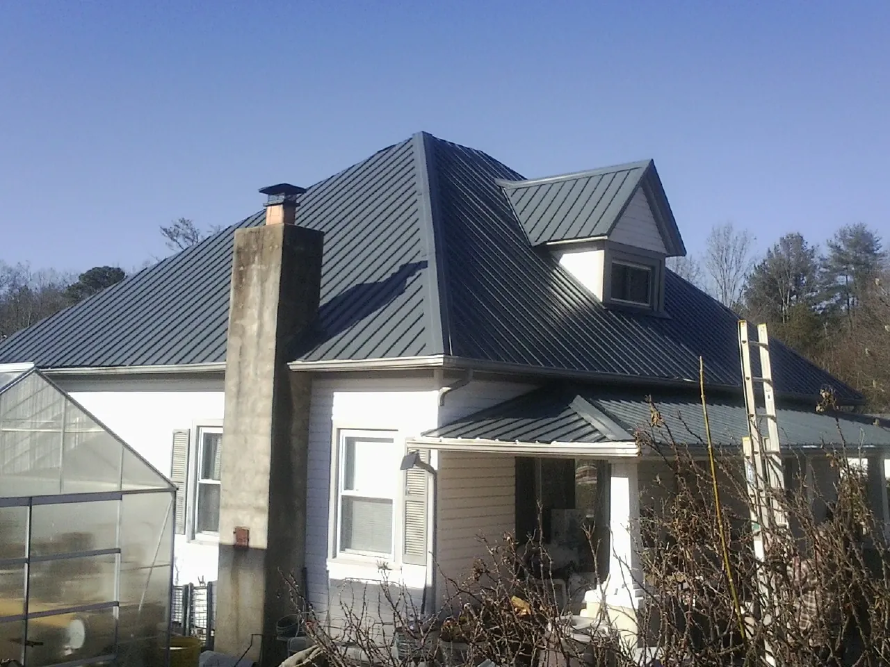 Dark blue standing seam metal roof on a white farmhouse with dormer — Slate & Tile Roof Repair by Roofing Brothers in Rock Hill
