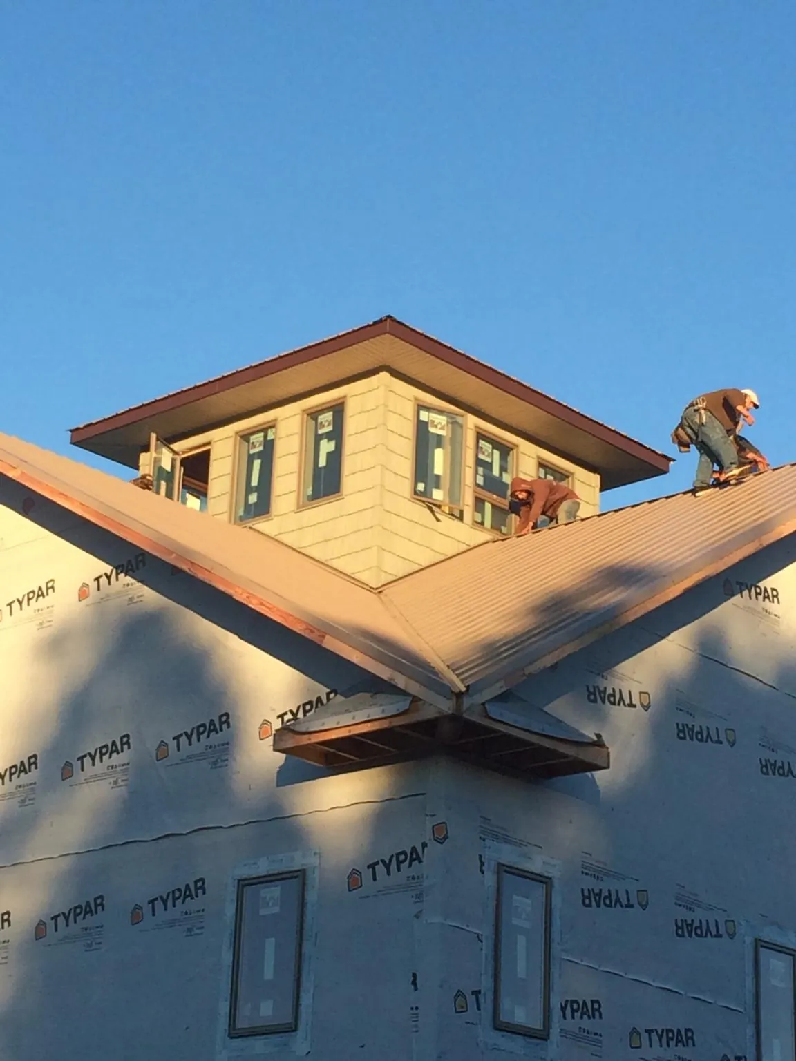 Roofers working around a rooftop cupola on a new metal roof at sunset — Roof Waterproofing in Rock Hill by Roofing Brothers